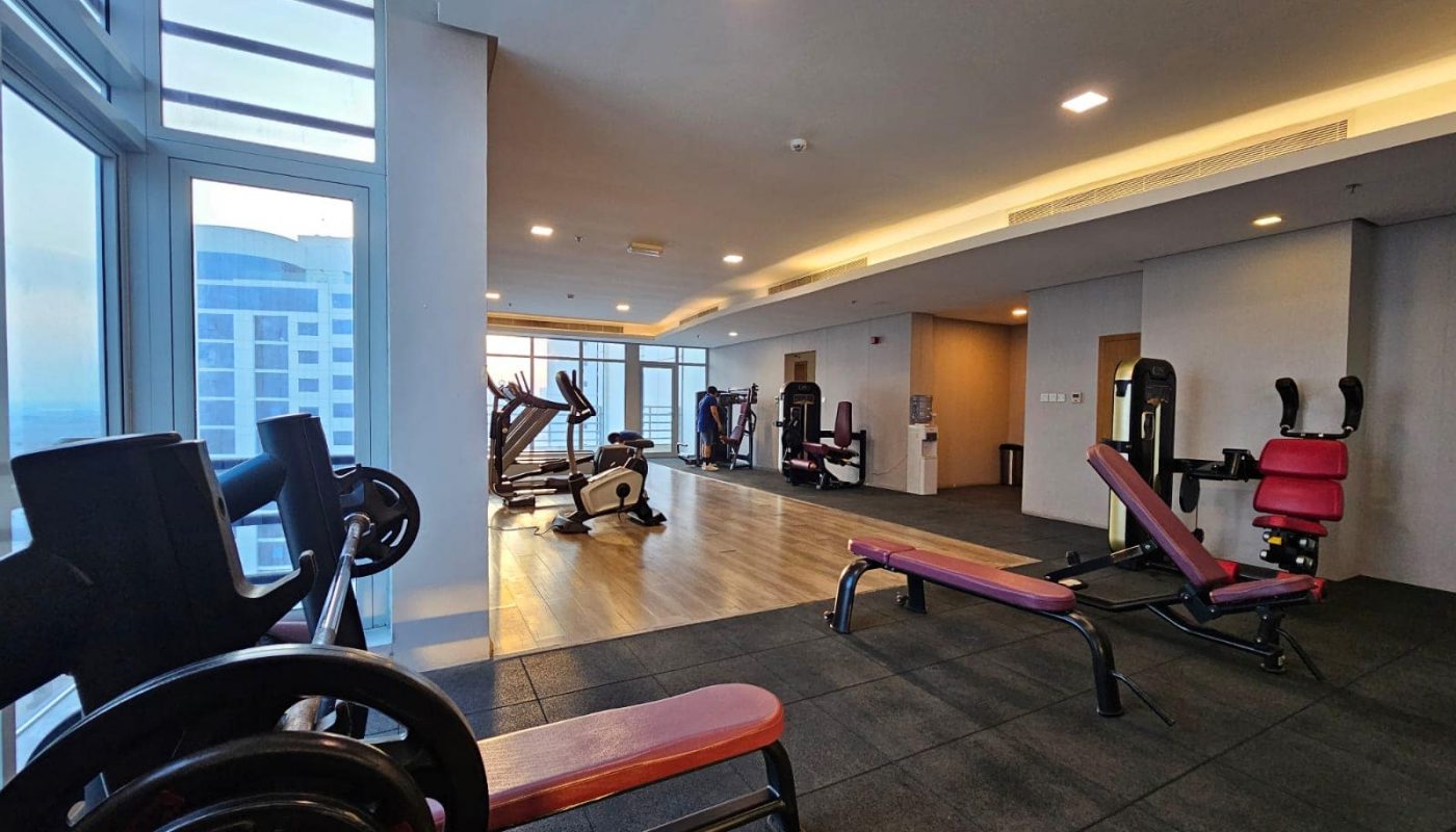 Modern gym with exercise equipment near large windows offering a city view and auto draft.