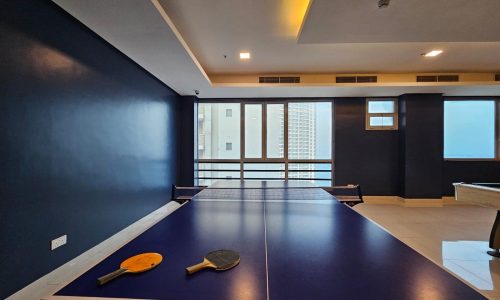 An Auto Draft indoor ping pong table with two paddles, set in a room with blue walls and a city view.