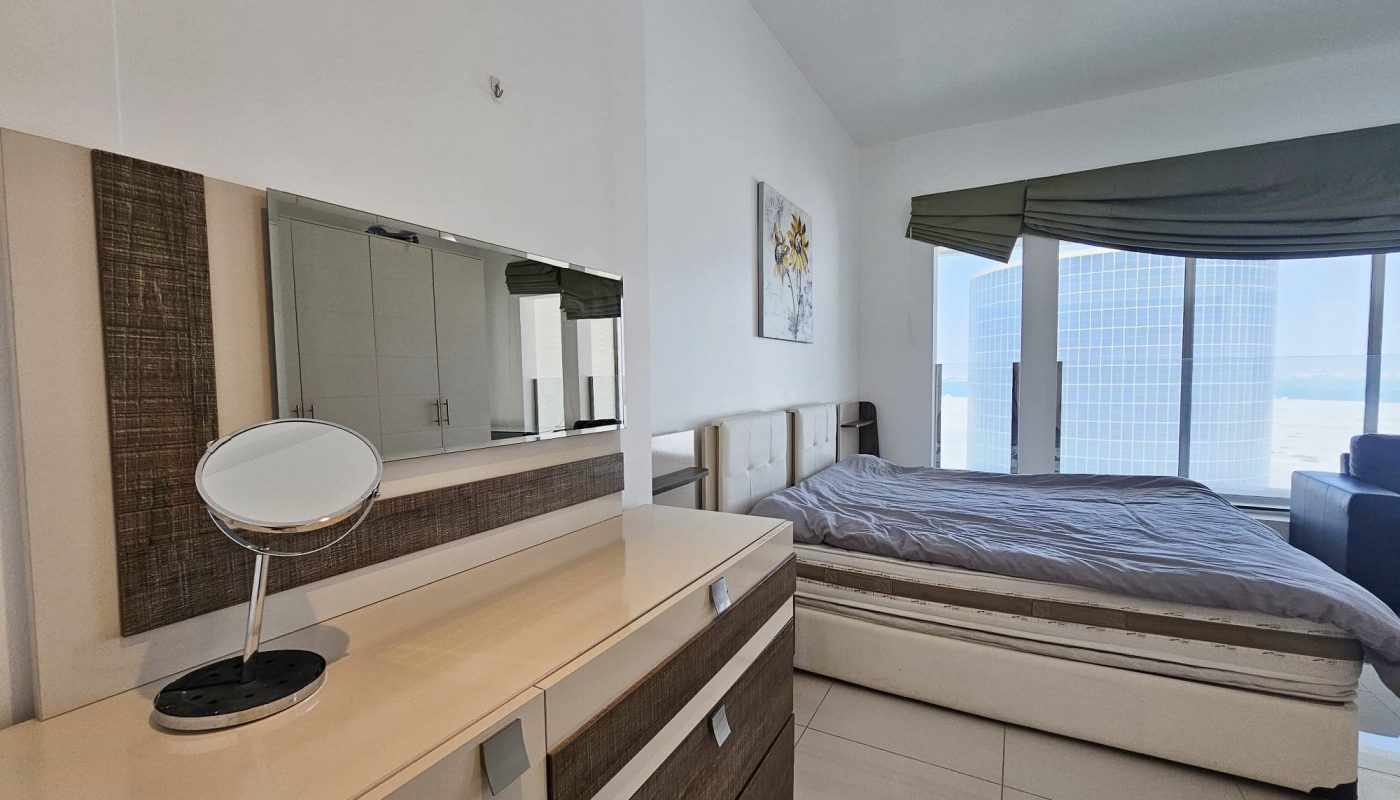 Modern 3 bedroom flat with a large bed, vanity mirror, and floor-to-ceiling window with city view.