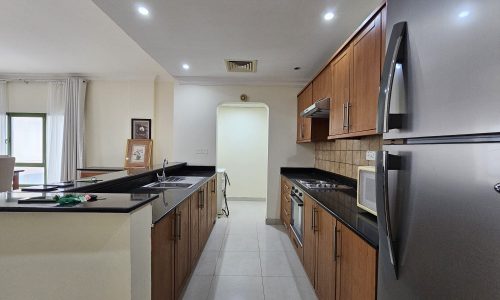 A well-lit, modern kitchen with wooden cabinets, stainless steel appliances, and a central island graces this 2BR Apartment for rent in Juffair.