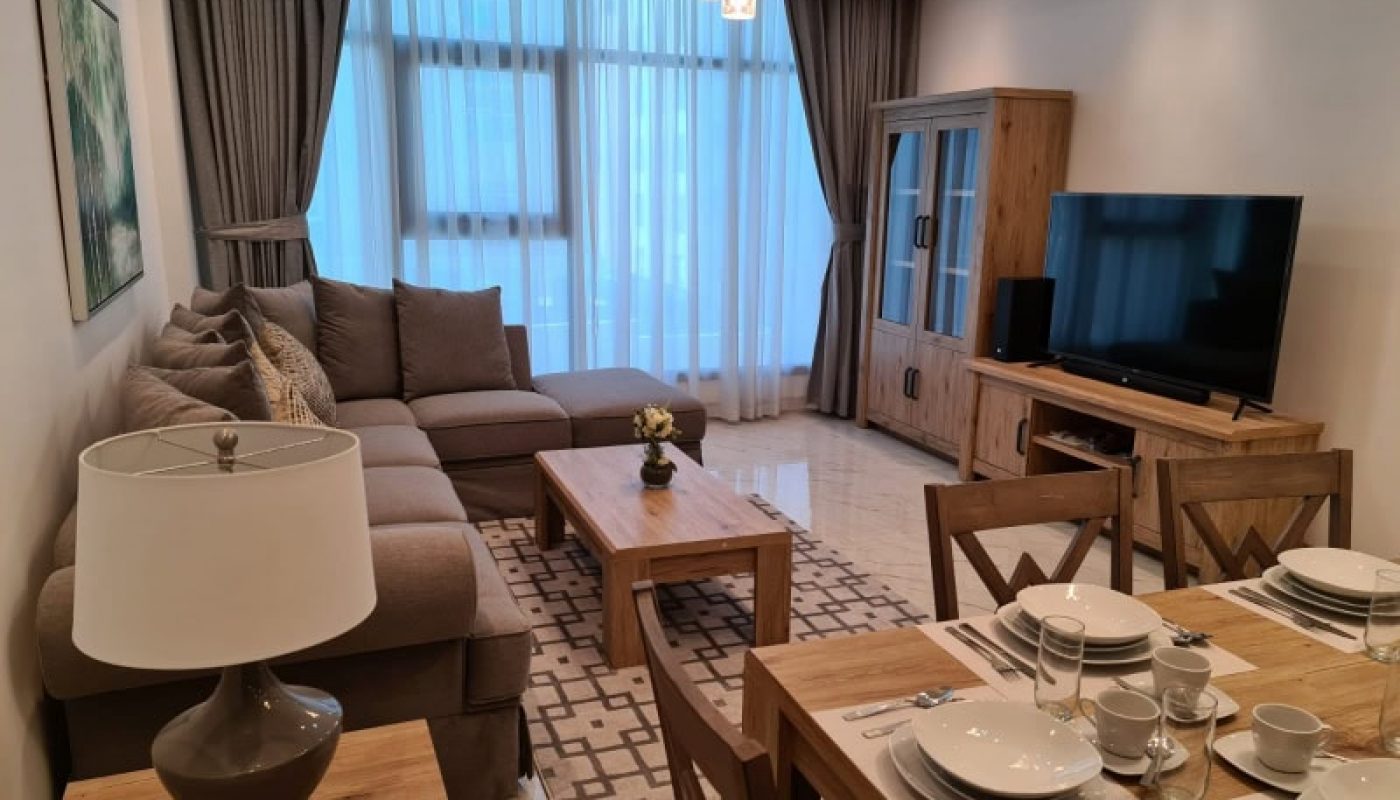 Modern living room with dining area, featuring a beige sofa, wooden furniture, and a television set - Auto Draft.