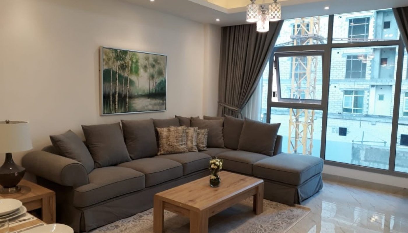 A modern living room with a large gray sectional sofa, wooden coffee table, and an abstract painting above the sofa features Auto Draft technology.