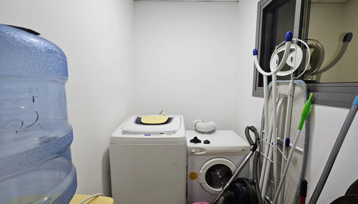 A fully-furnished utility room with a washing machine, water cooler, and various cleaning supplies.