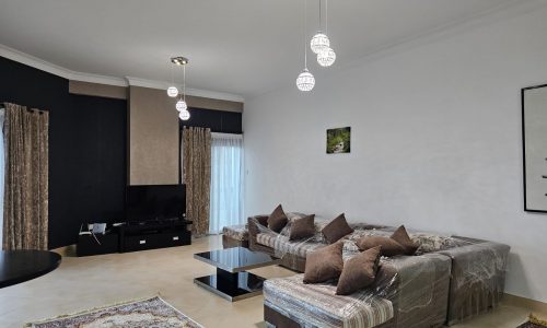 Modern TWO BEDROOM apartment in Juffair with l-shaped sofa, pendant lights, and a flat-screen TV.