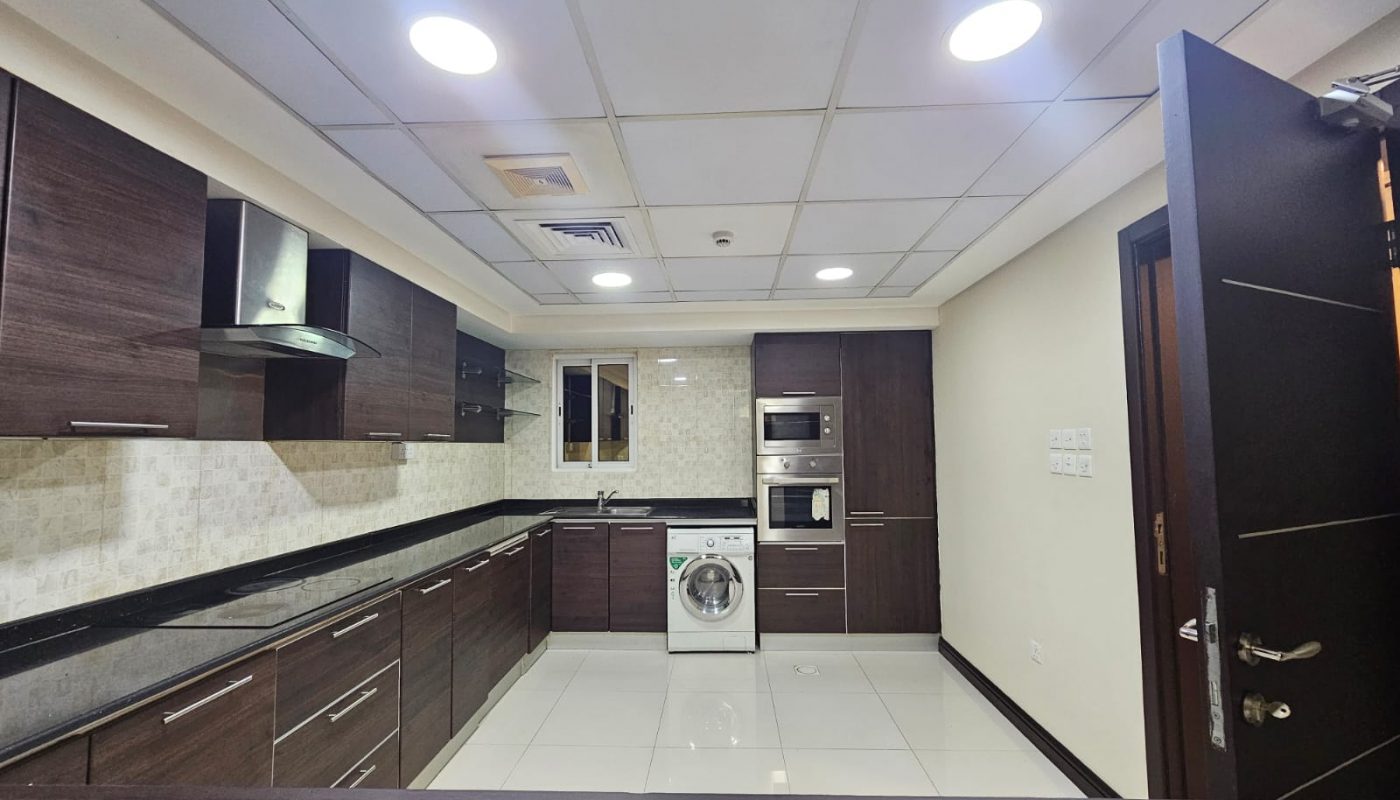 Modern 3BR apartment kitchen interior with dark wood cabinets, stainless steel appliances, and recessed lighting.