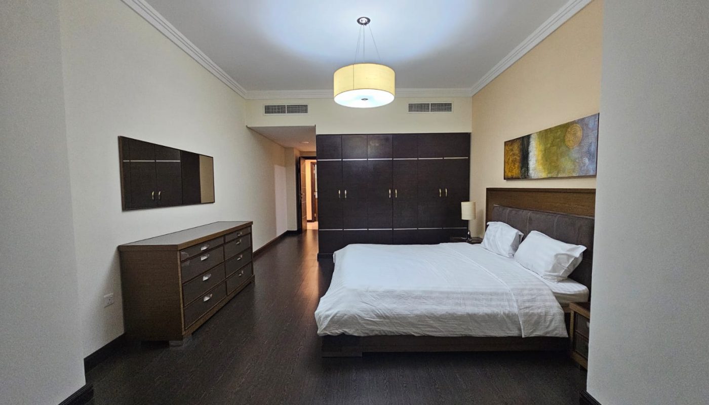 Modern 3BR apartment bedroom with a large bed, wooden furniture, and minimalistic decor.