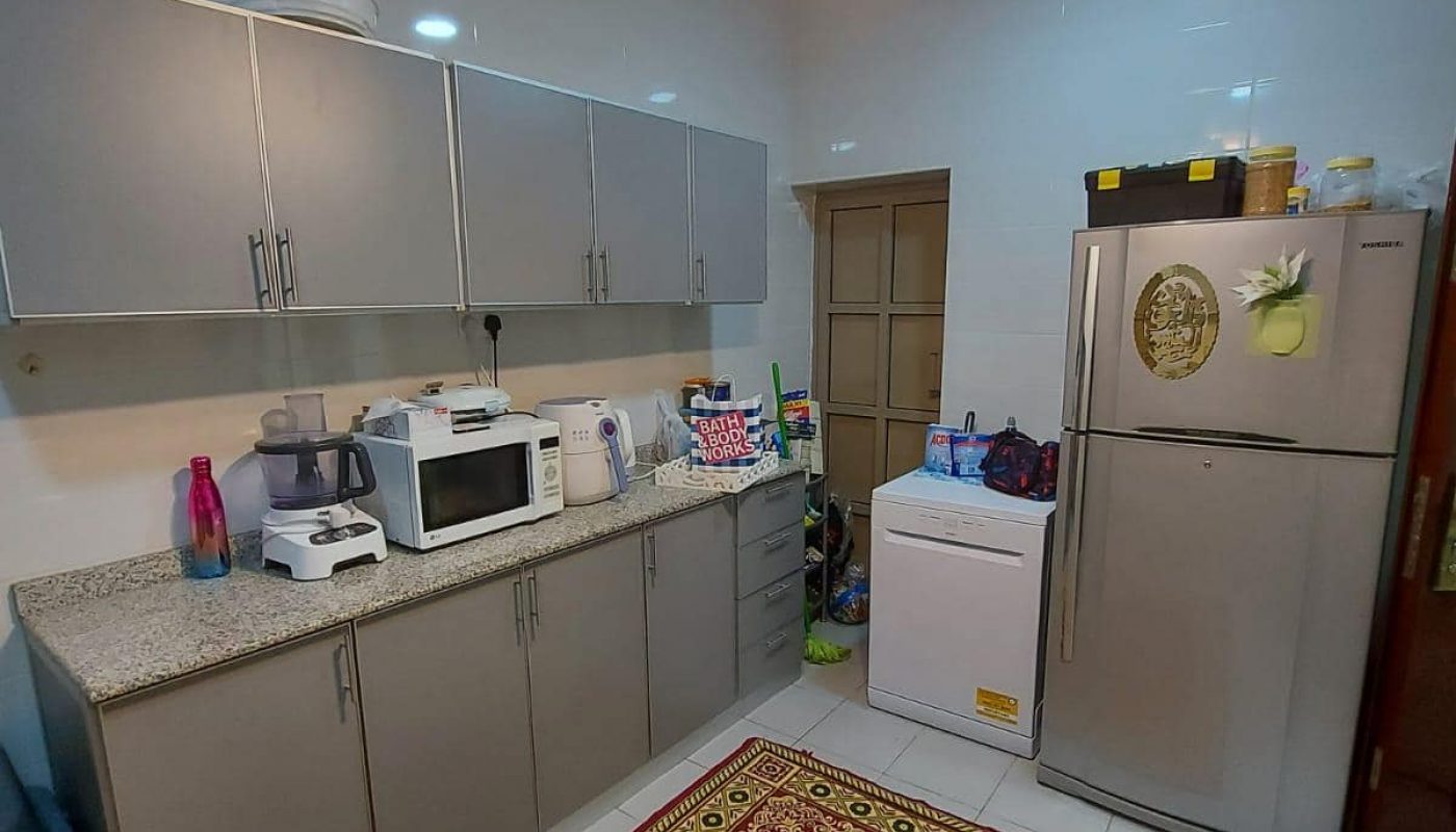 A modern kitchen in the Family 3BR Villa with white cabinets, a microwave, and two refrigerators, illuminated by ceiling lights above a decorative red rug.