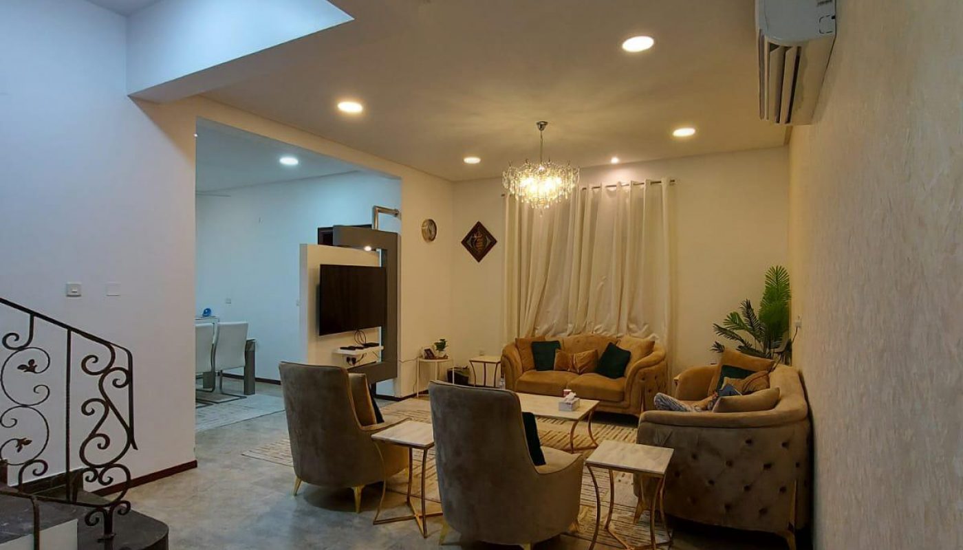 Elegant living room in a family 3BR villa with plush seating, chandelier, marble floors, and soft lighting, opening into a dining area.