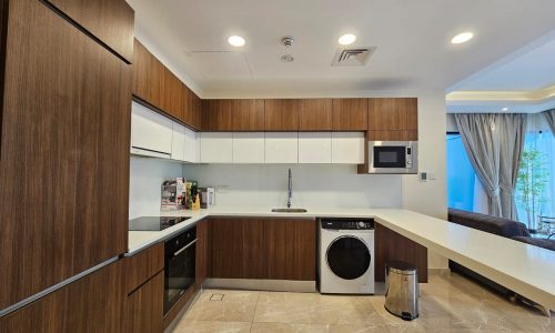 Modern kitchen with wooden cabinets, built-in appliances, and marble flooring, featuring a view of a curtain-covered window.