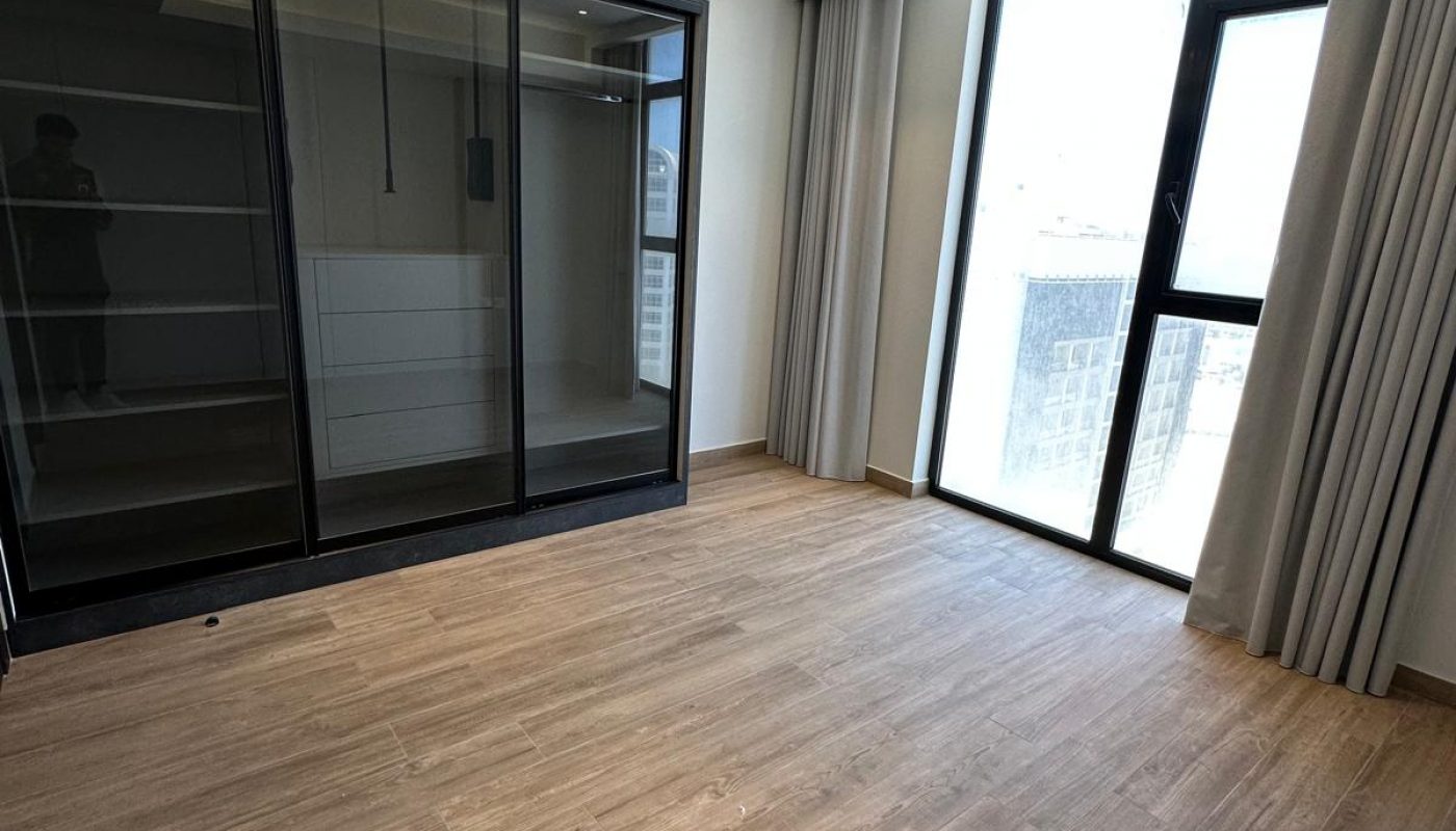 Empty modern room with wood flooring, large black glass wardrobe, floor-to-ceiling window, light-colored walls, and ceiling lights.