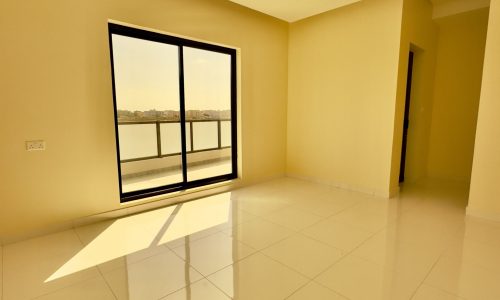 Empty room in the Luxury 4 Bedrooms Villa with sunlight casting shadows on the floor, a large window offering a view of the outdoors, and a closed door to the side.