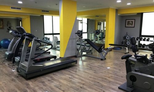 A gym room with yellow walls and yellow tread machines.