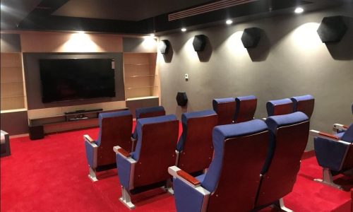 A luxury home theater in Juffair with red seats and a TV.