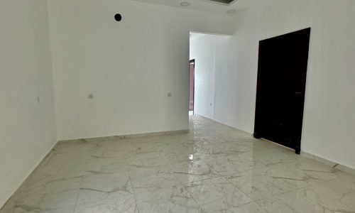 An empty room with marble floors and a ceiling fan, available for sale in the luxurious Al Bahair apartment.