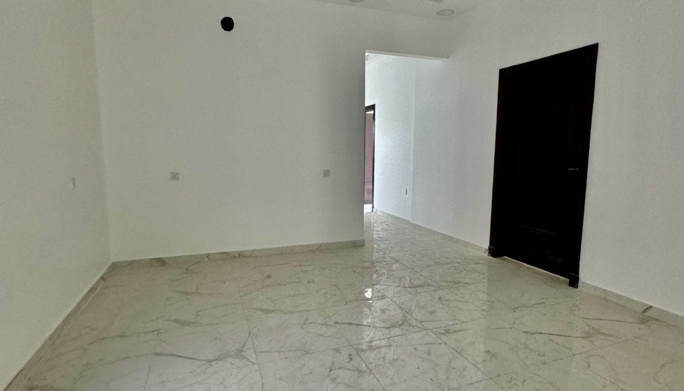 An empty room with marble floors and a ceiling fan, available for sale in the luxurious Al Bahair apartment.