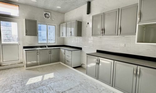 A luxury apartment with white cabinets and a ceiling fan in Al Bahair, available for sale.