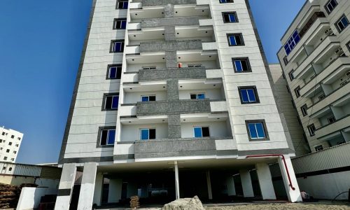 A luxury apartment building under construction with dirt and sand.