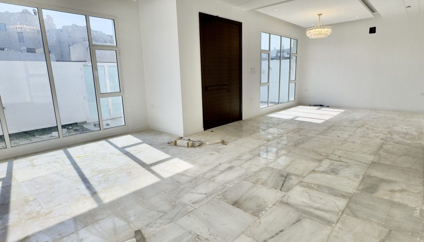A luxurious living room with marble floors, large windows, and a sale of a 5BR villa.