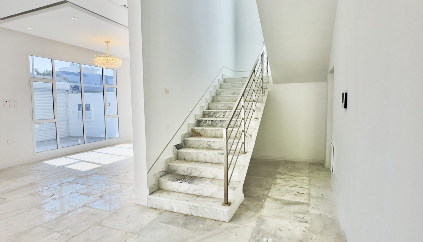 A luxurious marble floored room with a stunning chandelier and grand stairway in the Saar area.