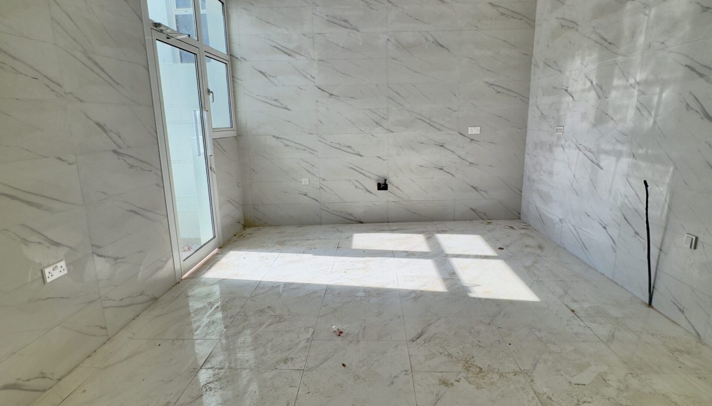 For Sale: A luxury 5BR villa with an empty room featuring marble floors and a sliding glass door.