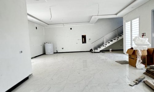 An elegant large empty room with marble floors and stairs.