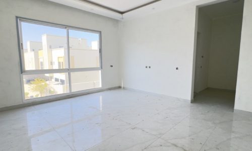 An elegant, empty room with white tile floors and a large window available for sale.