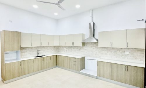 A white cabinet kitchen with a ceiling fan.