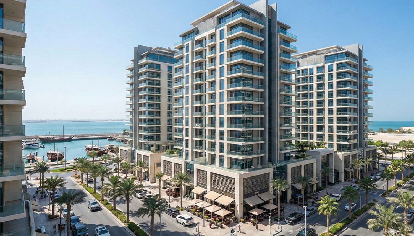 Modern high-rise buildings with glass balconies overlook a marina with yachts; palm trees line the busy streets filled with cars and outdoor cafes—capturing the vibrant lifestyle of in-demand areas like Juffair, Bahrain.