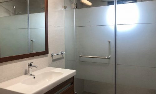 A spacious and luxurious apartment for rent in the Saar area, featuring a glass shower stall and sink in the bathroom.