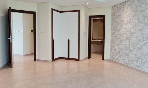 An empty room in a luxury complex with white walls and tiled floors for rent in Manama.