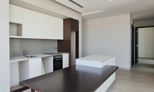 Outstanding 2BHK apartment for sale in Juffair with a white kitchen and wooden table and chairs.