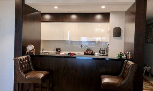 A modern kitchen with a bar and stools in a stunning 2BR apartment.