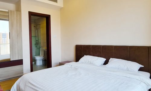 A luxury bedroom with a large bed and a bathroom in a 1BHK Apartment for Sale in Juffair.