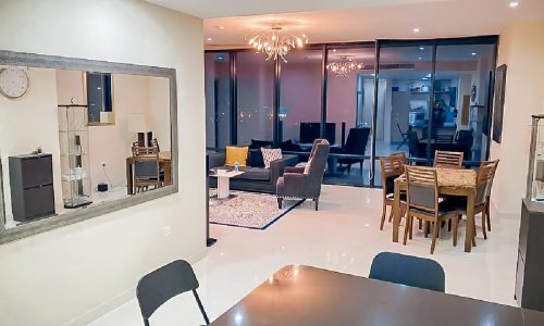 A modern living room and dining area in a luxury 2BR apartment for sale in the Seef Area.