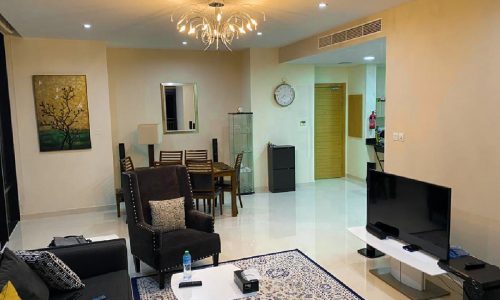 A luxury 2BR apartment for sale in Seef Area with a living room featuring a tv and a dining table.