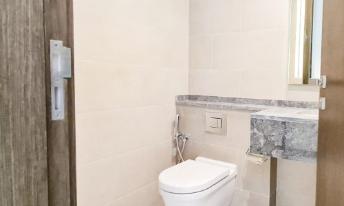 A luxurious bathroom featuring a toilet, sink, and mirror within a stunning 1BR flat for sale in Seef - Catamaran.