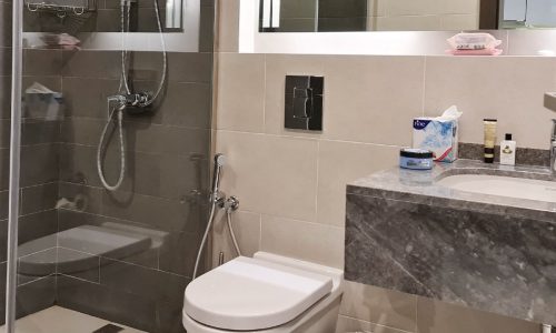 A luxurious studio in Seef featuring a spacious bathroom with a glass shower stall and toilet.