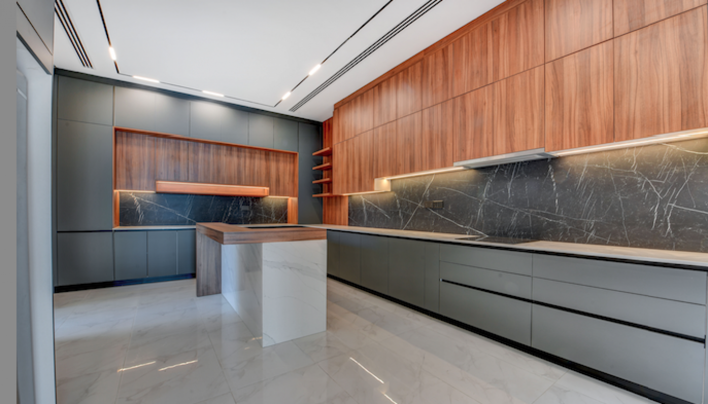 Modern kitchen with gray cabinets, wood paneling, marble floors, black marble backsplash, and an island with a wood and marble finish.