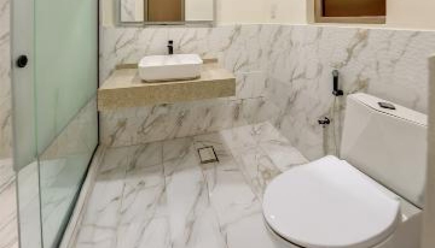 Modern bathroom with marble walls and floor, a glass-enclosed shower, a floating sink with a mirror, and a white toilet near a window.