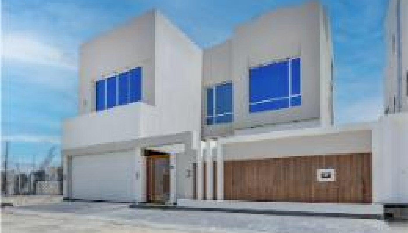 Modern two-story house with large windows, a wooden accent wall, and an attached garage under a blue sky.