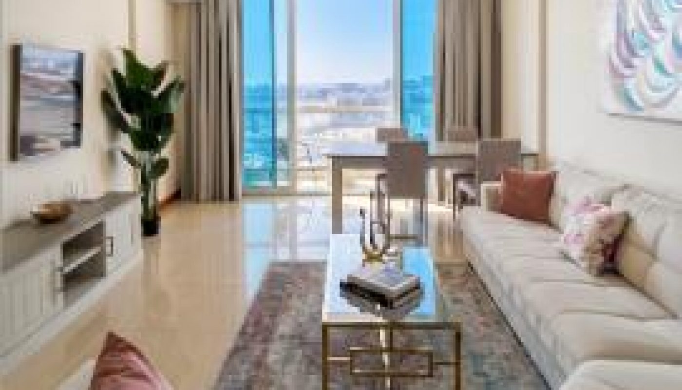Modern living room with two sofas, a coffee table, TV, large window with city view, dining area, and plant. Neutral tones and contemporary decor.