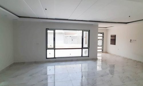 An empty room with marble floors and a sliding glass door in a new innovative villa for sale in Karranah.