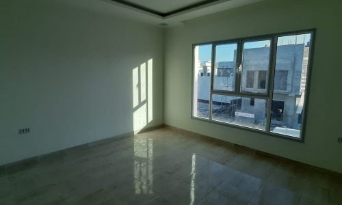 A spacious room with a large window and tiled floor.