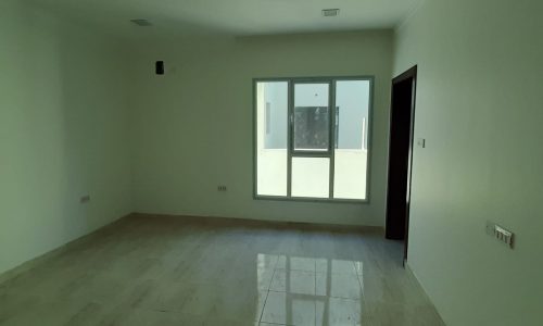 A 5BR villa for sale in Bani Jamra with a fascinating empty room featuring white tile floors and a window.