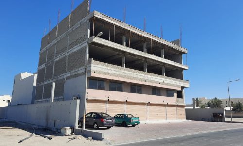 A commercial building under construction in West Eker, with a car parked in front.