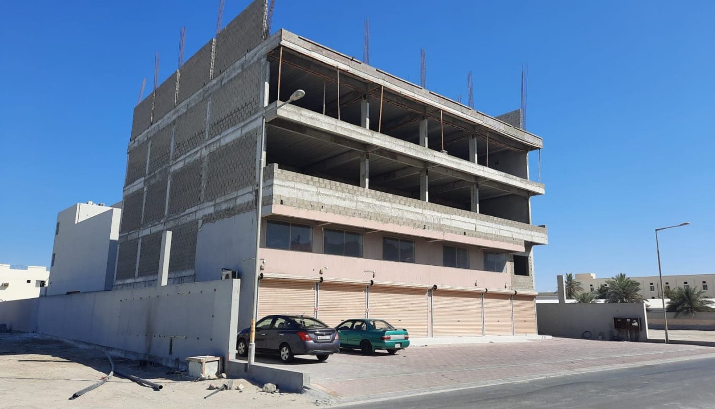 A commercial building under construction in West Eker, with a car parked in front.