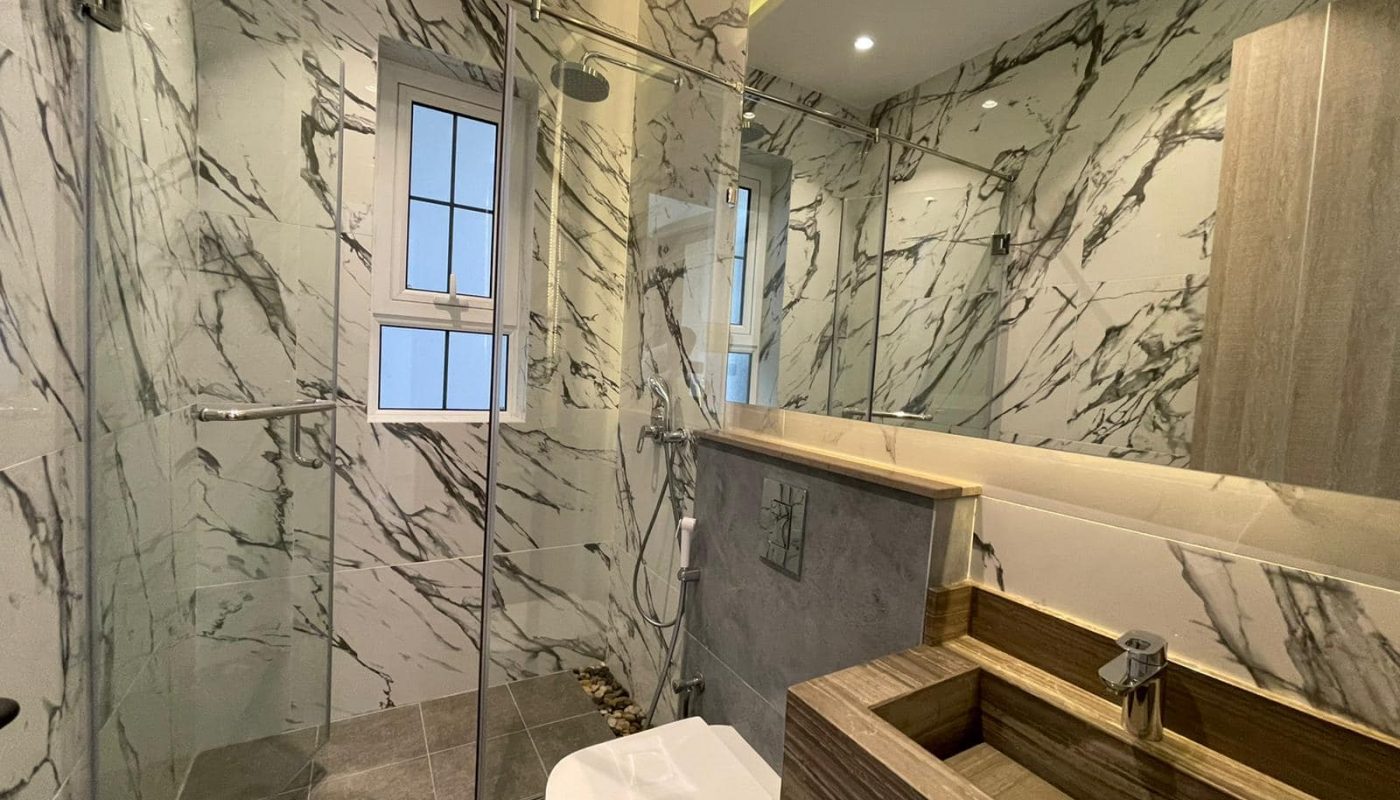 A luxury bathroom with marble walls and a glass shower in a villa.