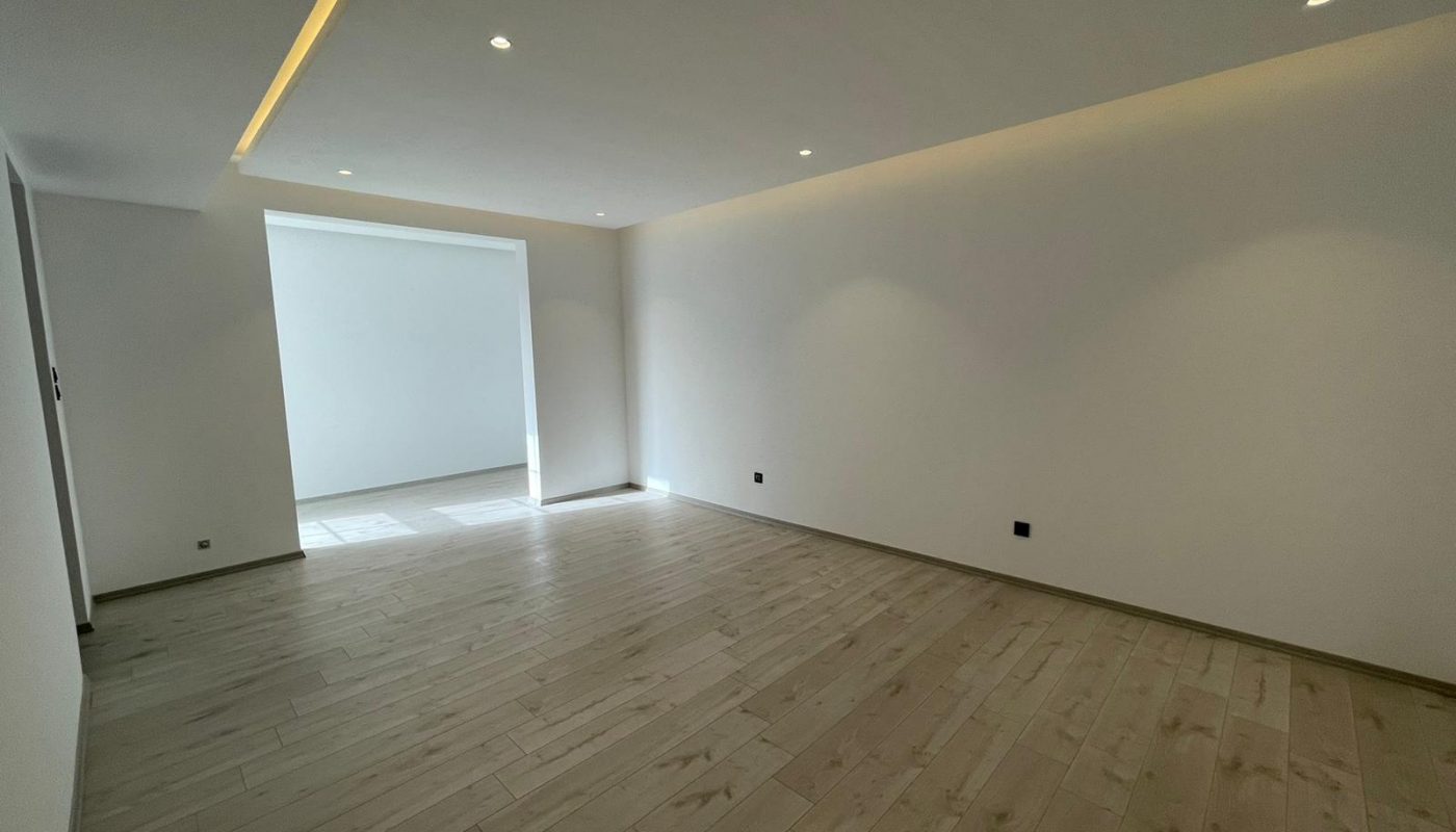 A luxury villa with five bedrooms featuring an empty room with white walls and wood floors.