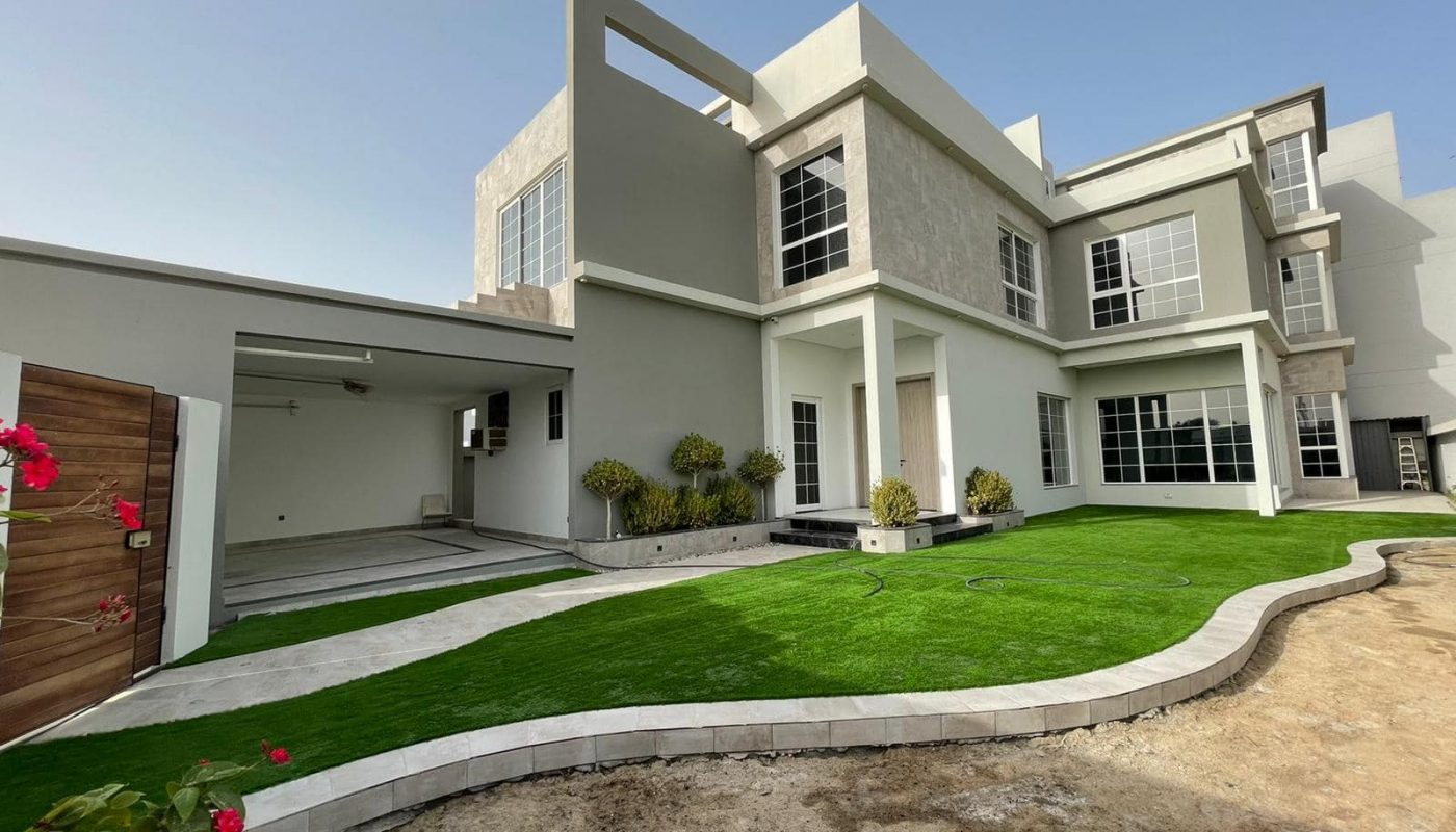 A modern luxury villa with artificial grass in front of it.
