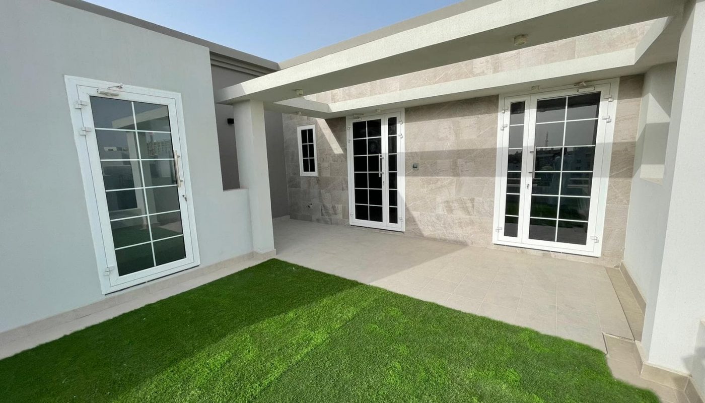 A luxury villa with artificial grass in front of it.
